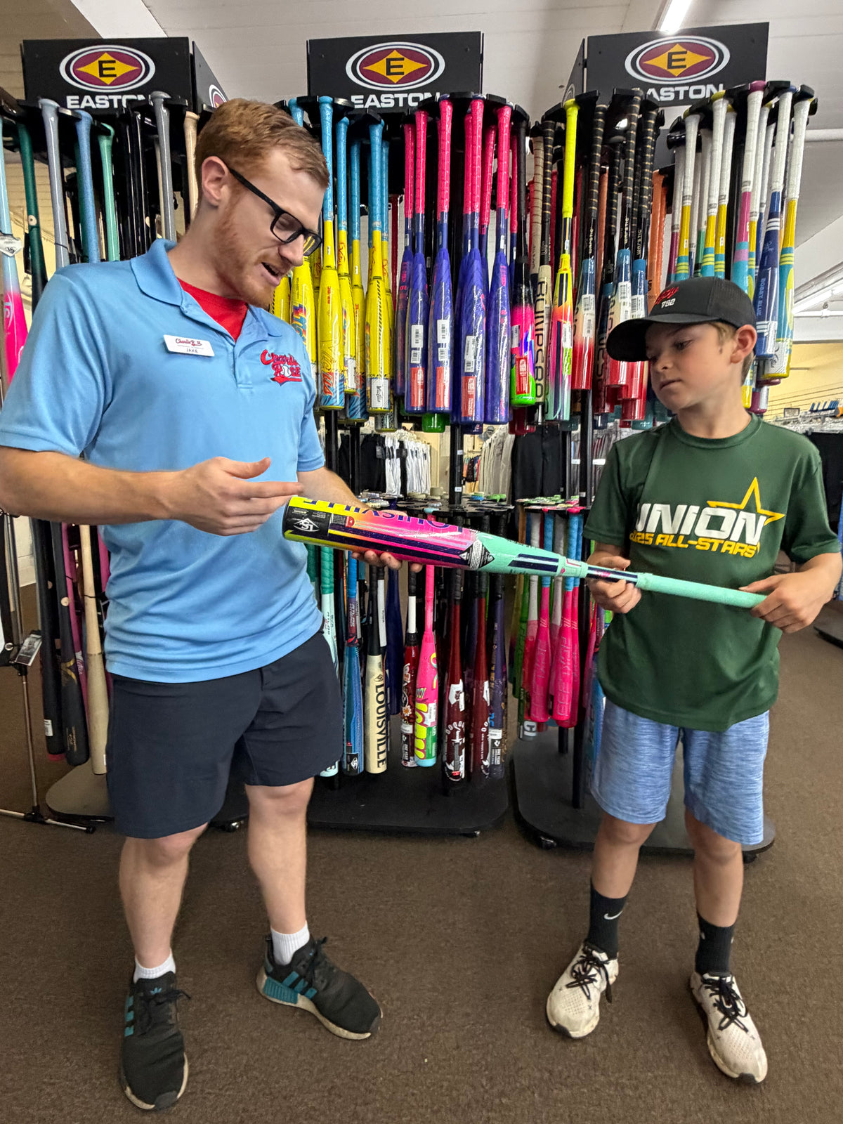 A staff member helping a young Union player select a baseball bat