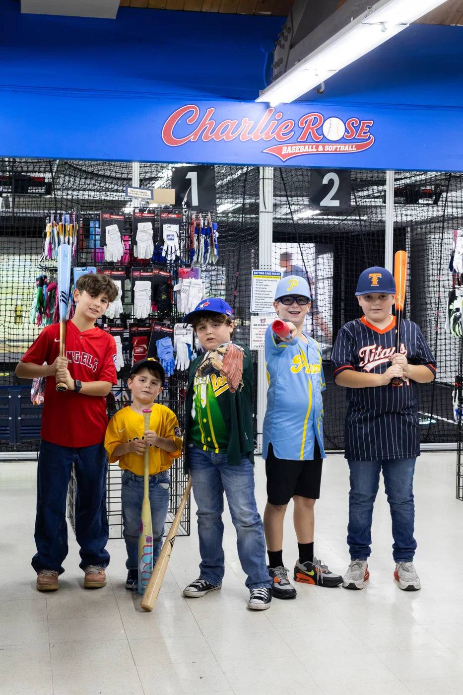 Young players posing with baseball bats inside the shop